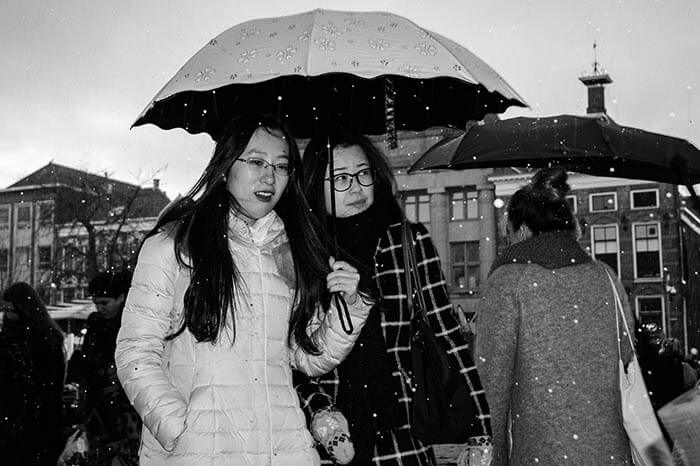 Vrouwen onder een paraplu tijdens een winterse bui in de stad Groningen.