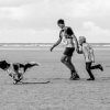 Berenloper samen met hond en kind op het strand.