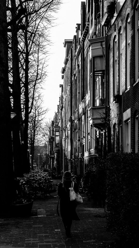 Een vrouw loopt weg van de camera op een straat in Groningen.