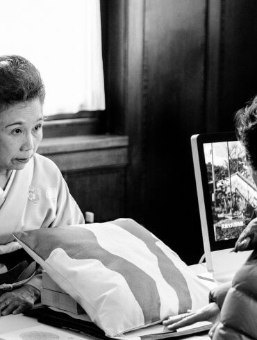 Een oudere Japanse vrouw in kimono praat met een bezoekster.