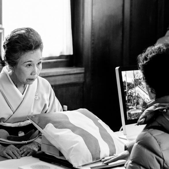 Een oudere Japanse vrouw in kimono praat met een bezoekster.