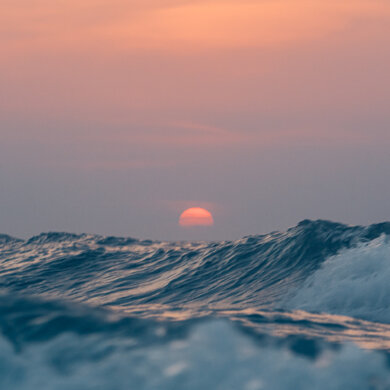 Zonsondergang vlak boven de hoge golven van de Noordzee
