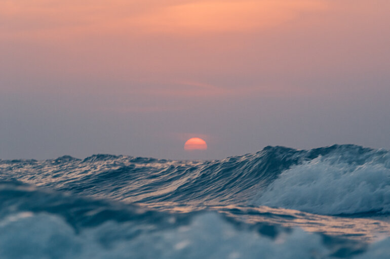 Zonsondergang vlak boven de hoge golven van de Noordzee