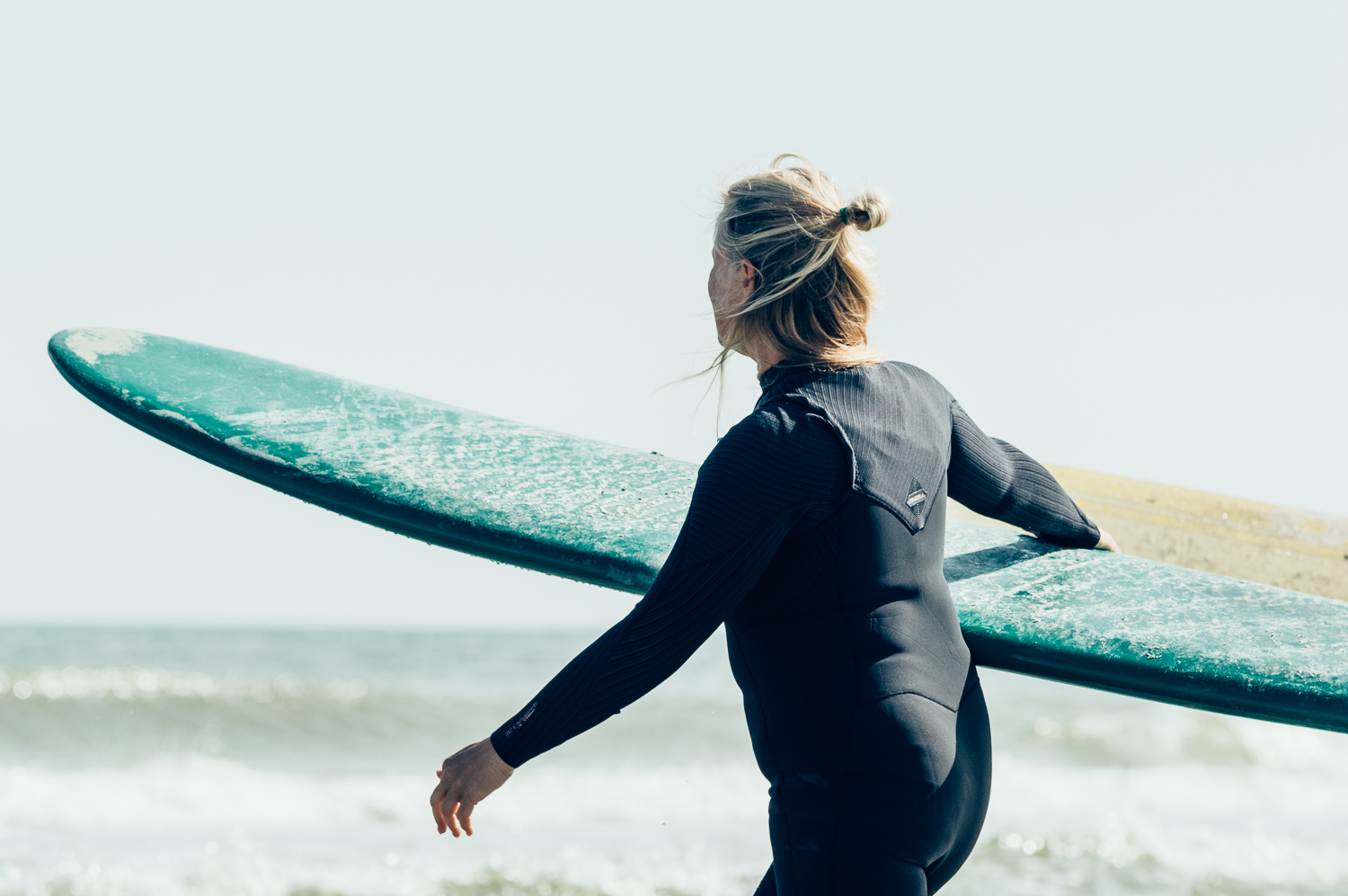 Anne-Marie Kaale loopt met haar surfboard naar het water