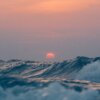 Rode ondergaande zon die de lucht rood kleurt vlak boven de blauwe golven van de Noordzee - Kunst in de Kerk 2022