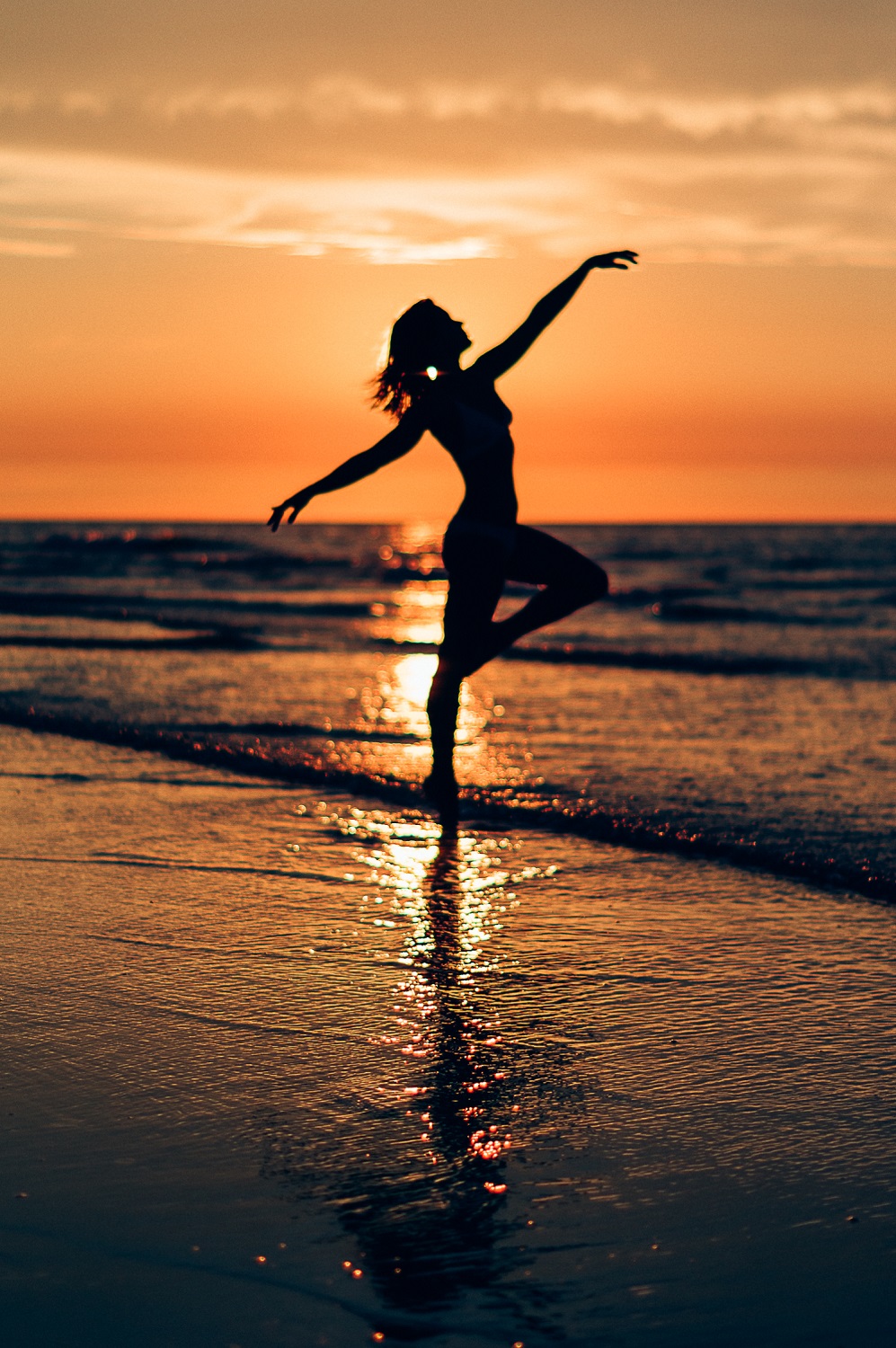 Silhouette van Margriet Haring die danst bij het water tijdens zonsondergang