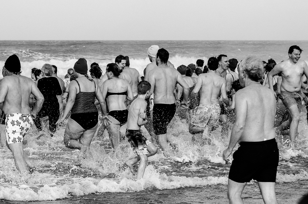 Deelnemers rennen het water in en uit