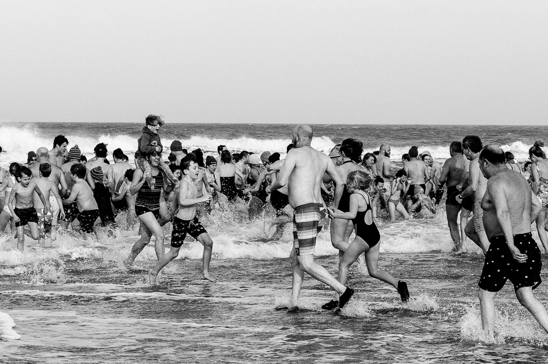 Deelnemers rennen het koude water in en uit